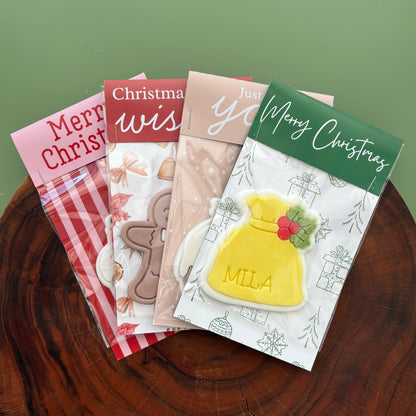 Collection of Christmas-themed cookie backing cards on a wooden surface with a green background