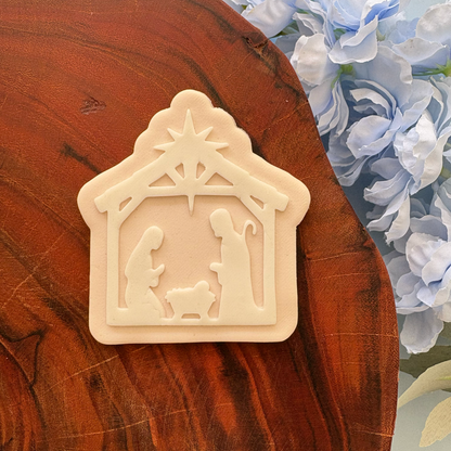 Decorative nativity scene on a wooden surface with flowers in the background