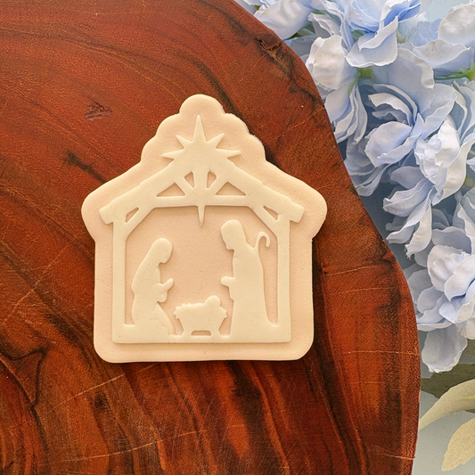 Decorative nativity scene on a wooden surface with flowers in the background