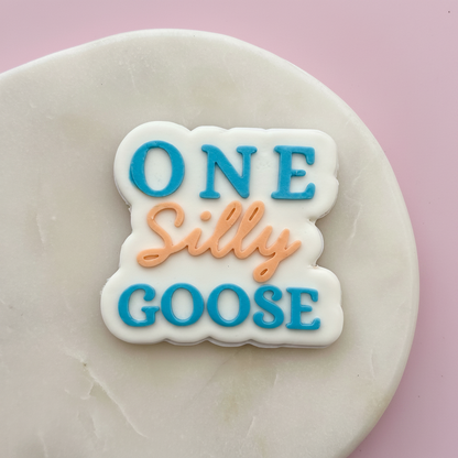 Decorative fondant with 'ONE Silly GOOSE' text on a pink background