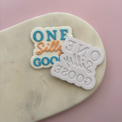 Two cookie cutters with text on a pink background