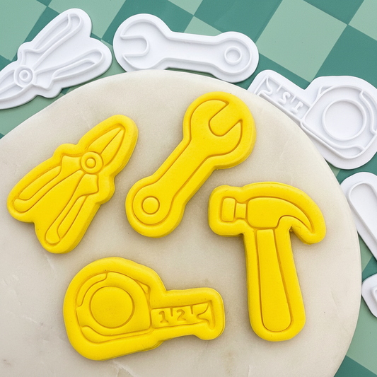 Yellow tool-shaped cookie cutters on a green checkered background