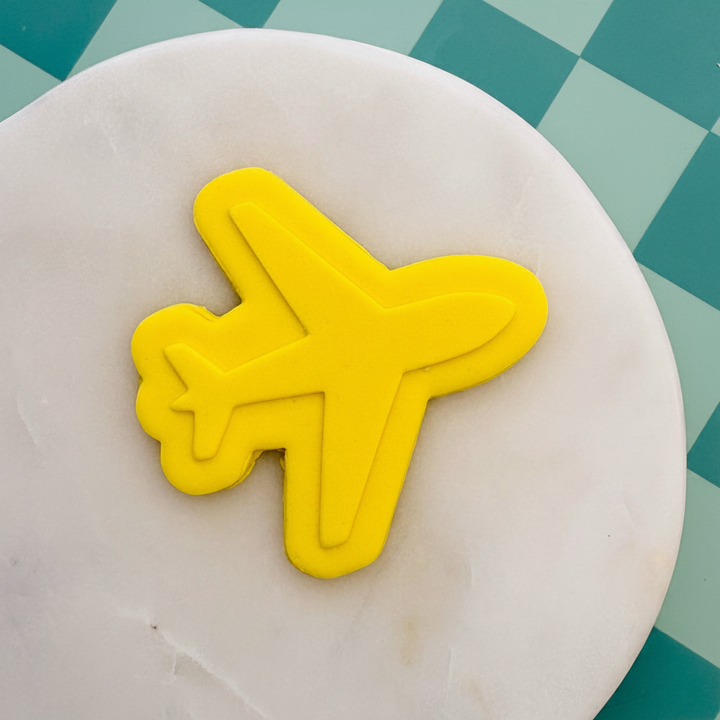 Yellow airplane cookie cutter on a marble surface with a checkered background